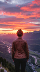 Naklejka premium Back view of woman watching vivid sunset from mountaintop overlooking winding river and valley
