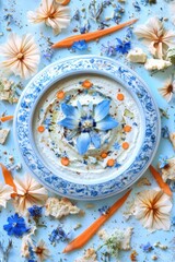 Artistic hummus presentation overhead shot with blue flower carrot and bread decoration on light blue background