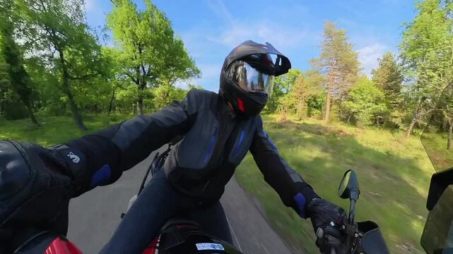 Motard sur route de campagne, au printemps, dans une for&ecirc;t, sous le soleil