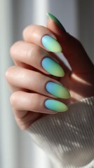 Colorful gradient nail design showcasing a stylish blend of green and blue hues in a modern, soft lighting environment