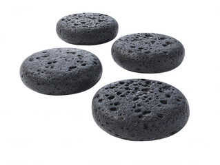 Four dark gray porous volcanic lava stones are artfully arranged on a pure white background creating a simple yet elegant natural design to inspire wellness.