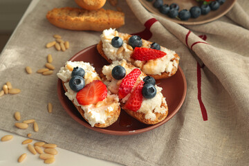 Crostini with ricotta, berries, pine nuts. Slices of toasted bread with cheese for breakfast. A...