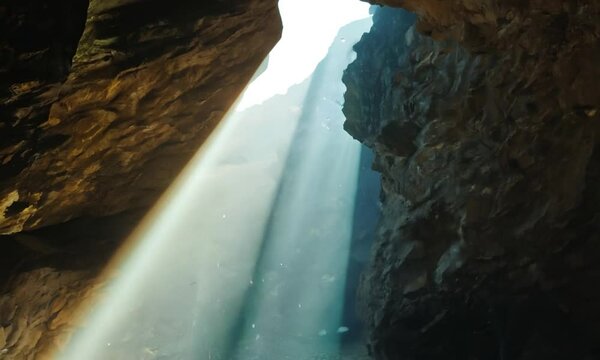 A light shines through a cave in the mountains