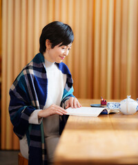 ティータイムに読書を楽しむ50代女性