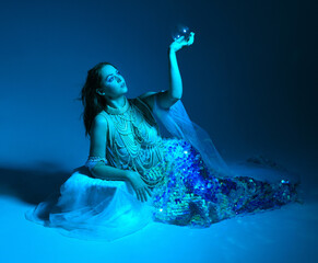 Fantasy studio portrait of a red-haired mermaid faery model wearing white pearl gown, fairytale...