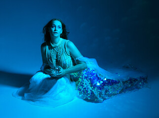 Fantasy studio portrait of a red-haired mermaid faery model wearing white pearl gown, fairytale...