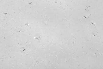 Rain drops on a window pane create a natural texture. Transparent liquid element for background or overlay effect concept on a gray surface.