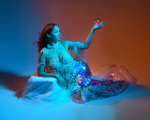 Fantasy studio portrait of a red-haired mermaid faery model wearing white pearl gown, fairytale...