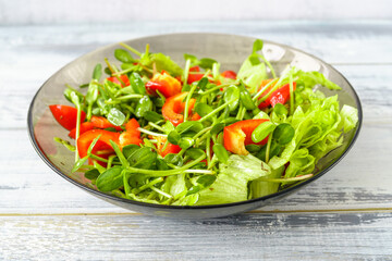 Fresh vegetable salad with micro greens and red pepper in a transparent bowl. Concept of healthy nutrition using for cookbook or food blog.