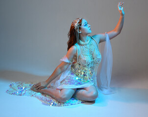 Fantasy studio portrait of a red-haired mermaid faery model wearing white pearl gown, fairytale...