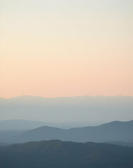 Serene Mountainscape at Dawn, A Faded Silhouette of Peaks Emerging from a Gentle Mist, Embracing Tranquility and the Subtle Hues of the Rising Sun