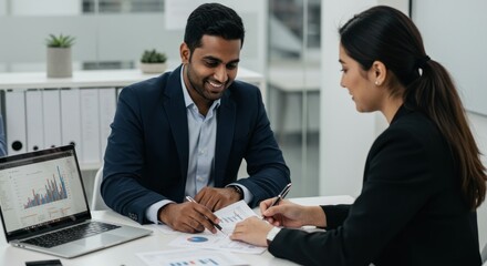 Two business professionals collaborate on financial planning in a modern office