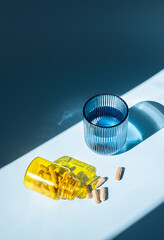 Pills and Water. Yellow Bottle with Spilling Some Capsules. Medicine, Pharmacy and Healthcare for Wellness Advertising.