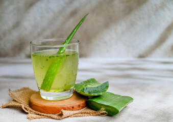 Fototapeta premium Fresh aloe vera drink in glass cup with aloe slices 