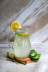 Fresh aloe vera drink in glass jug with aloe slices 