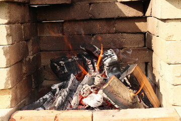 Fire with flames and embers on a barbecue. Stone barbecue. Burning stone barbecue firewood with...