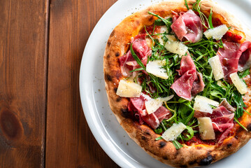 Pizza italiana con prosciutto crudo, scaglie di grana e rucola 