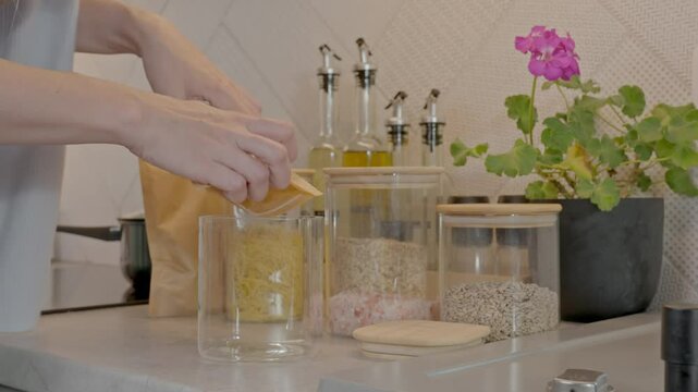 Slow motion scene of a woman filling a jar with ground ginger