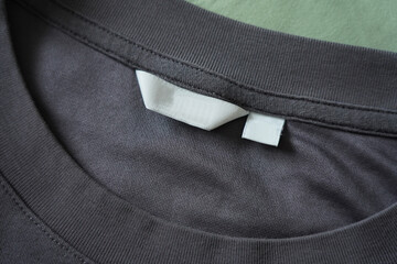 Close up of blank white clothing care label on black shirt fabric background.