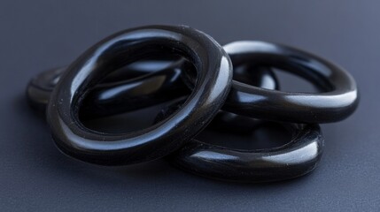 Three glossy black licorice rings piled on a dark gradient background studio shot confectionery concept for food blogs or candy promotions 
