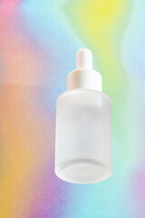 Bottom view of matte glass bottle with pipette on rainbow background. Cosmetic product packaging presentation. Unbranded dropper bottle