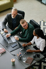 Group of business professionals discussing project strategy around conference table, with man...