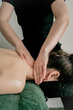 Female massagist massaging client's neck