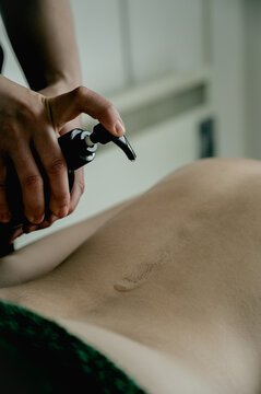 Massagist woman pouring massage oil on client's back