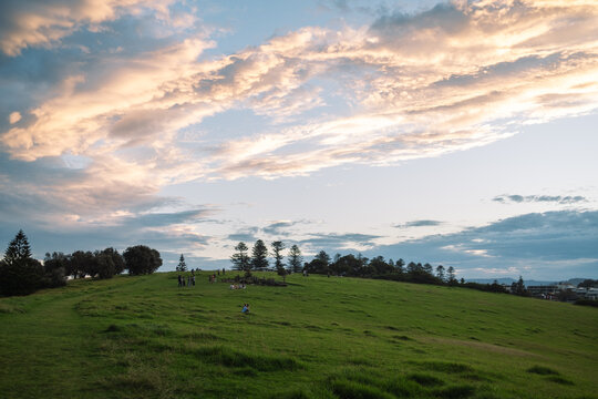Groups of people gathered on a green hilltop at sunset in Gerringong