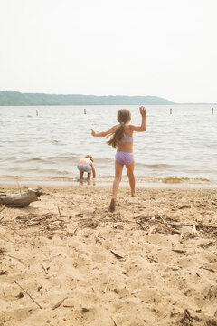Two kids playing on a sandy lakeshore on a summer day.