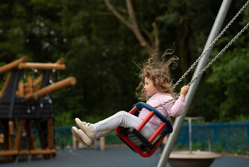 Side view of girl swinging in playground