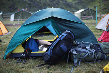 A tent and backpacks set up in the park for hiking.
