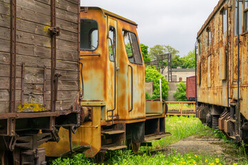 Old, rusty railway wagons standing on a siding, surrounded by greenery. Visible signs of corrosion...