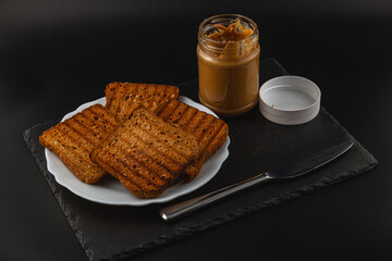 Peanut butter and toasted bread served on a black plate