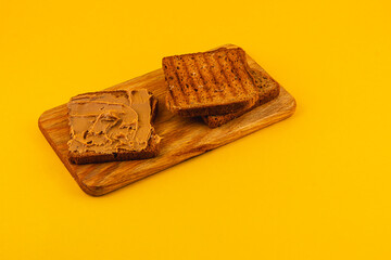 Toasted bread slices with peanut spread on wooden board
