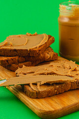 Peanut butter spread on bread with jar on wooden board