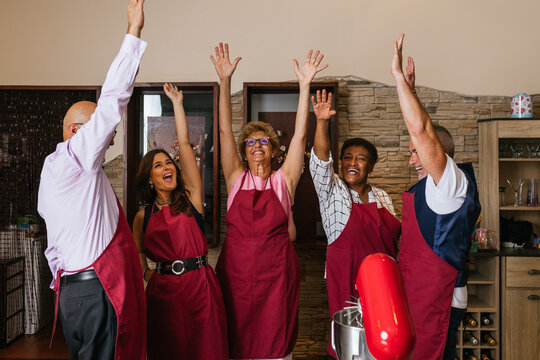 Happy chefs raising hands celebrating cooking class success