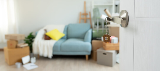 Moving house, relocation. The key was inserted into the door of the new house, inside the room was a cardboard box containing personal belongings and furniture. move in the apartment, banner
