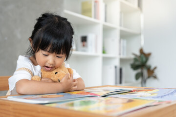 Happy Asian children relax read story book for bear doll. daughter and reading a story. learn...