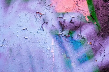Colorful wall with peeling paint in pastel hues, purple, pink. Textured surface, urban graffiti,...
