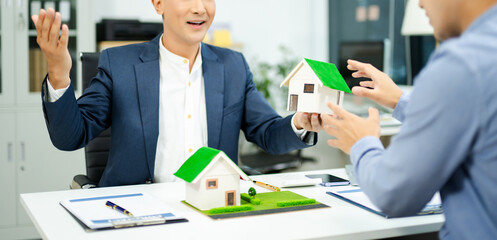 Real estate agent consulting with buyer on house model and pricing using calculator in modern...