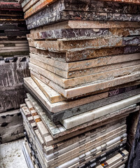 Variety of stone tiles stacked in workshop with natural light illuminating textures. High quality photo
