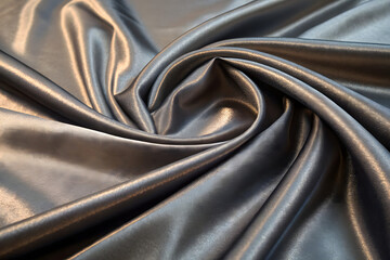A close-up view of smooth, flowing golden silk fabric, with elegant curves and highlights reflecting light to create a luxurious and fluid texture.