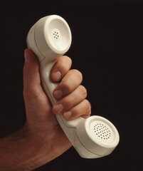 Hand hold retro telephone handset on black background.