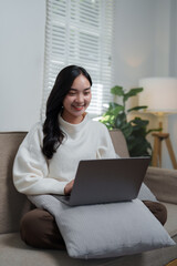 Young woman working remotely from home using laptop on sofa