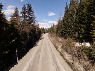 Scenic Mountain Road Through Evergreen Forest In BC, Canada During Clear Day