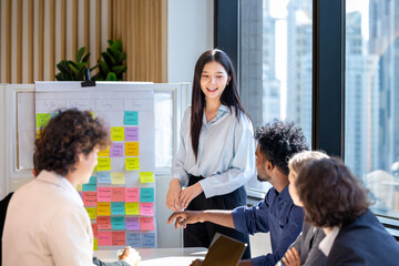 Asian woman sale manager is showing annual report chart to her colleagues in executive meeting for...