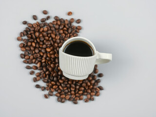 Black Coffee in White Ribbed Mug Surrounded by Roasted Beans Flat Lay
