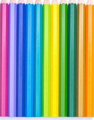 Obraz premium A row of brightly colored crayons arranged in a gradient pattern on white paper.