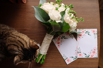 Wedding day. Beautiful tabby cat posing near the wedding bouquet